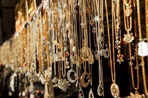 A seemingly endless collection of gold necklace pendants hanging in an open market