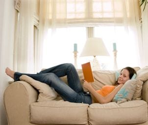 Woman wearing jeans and reading on the couch